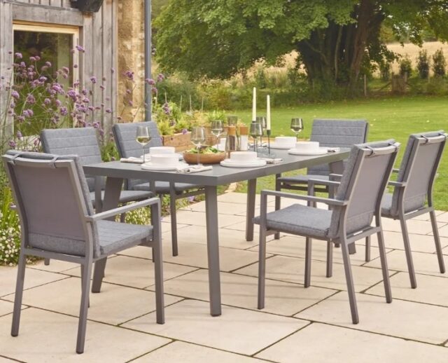 Outdoor dining set of silver table and chairs in bright garden setting