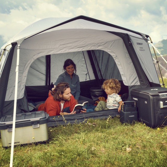 Mum, dad and toddler reading together in grey tent