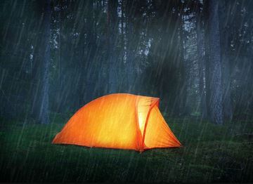 Small, illuminated tent on a rainy night.