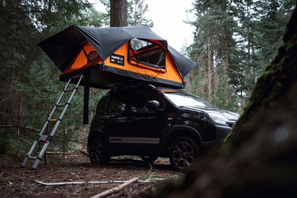 Open TentBox on top of black car in wooded area